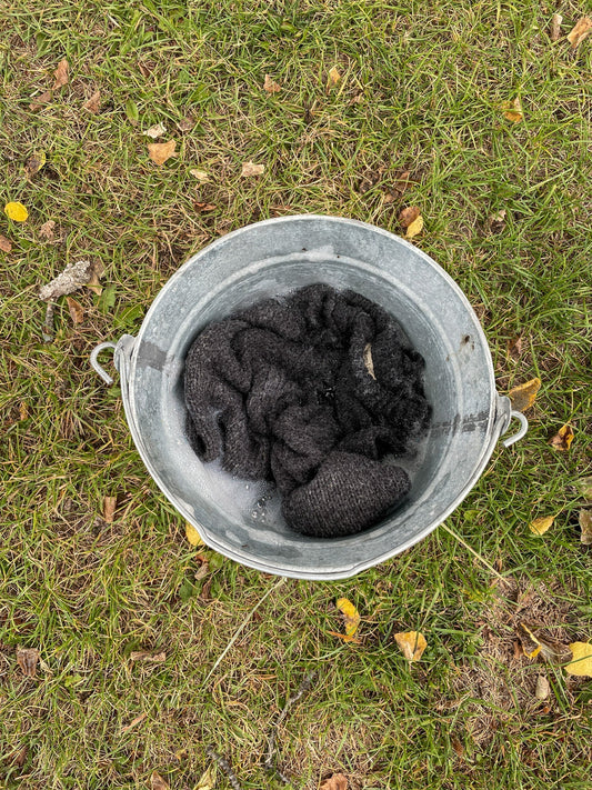 Wool sweater soaking in mild detergent in a bucket 