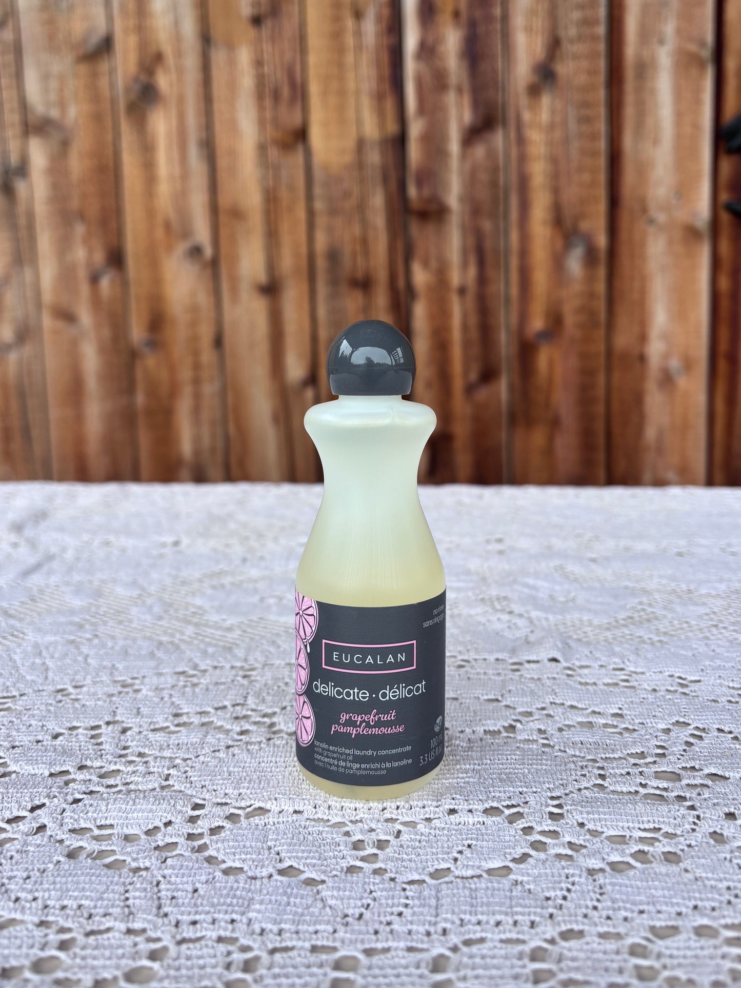 Bottle of Eucalan soap on a lace tablecloth with a wooden background