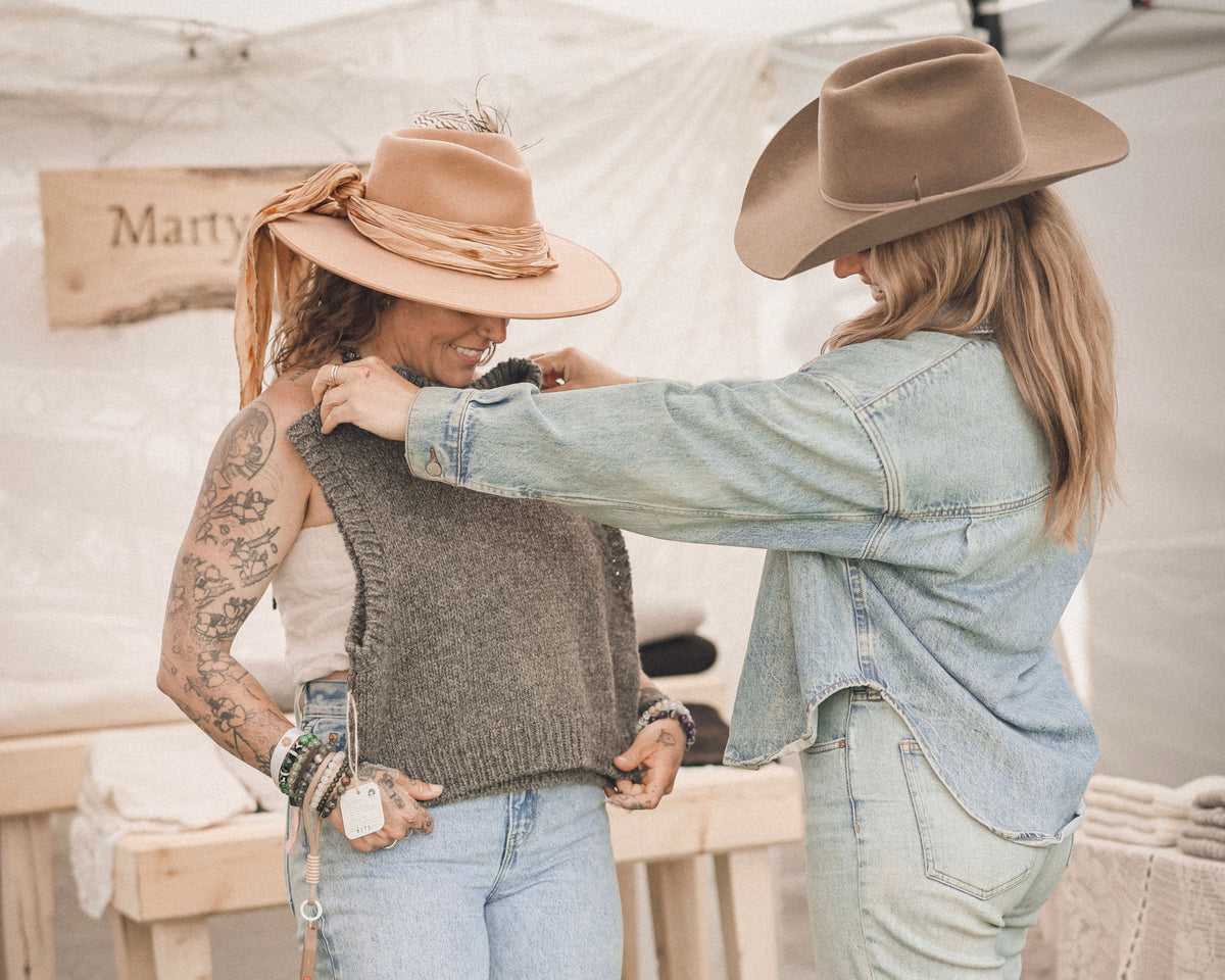 Jillian holding a wool vest up to a customer.